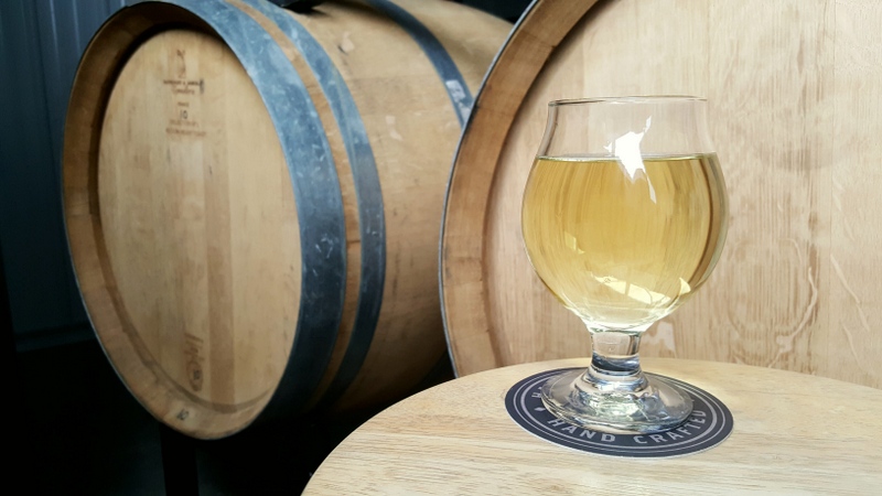 A glass of Bad Hombre by the tequila barrels